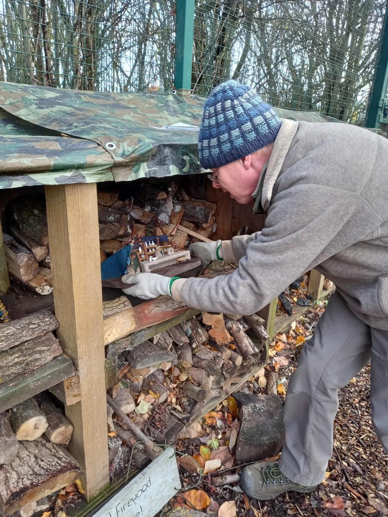 A man looking closely at a bug hotel